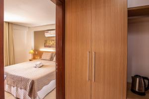 - une chambre avec un lit et un placard en bois dans l'établissement Linda Suíte em Apart-hotel com vista incrível!!!, à Cumbuco
