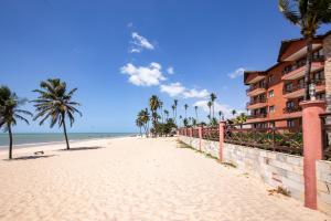 einen Sandstrand mit Palmen und ein Gebäude in der Unterkunft Linda Suíte em Apart-hotel com vista incrível!!! in Cumbuco
