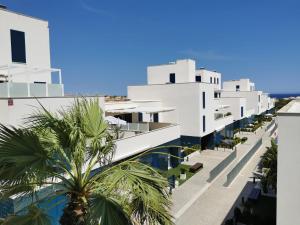 Blick auf die Seite eines weißen Gebäudes mit Palmen in der Unterkunft Turquesa del Mar - Max Beach Golf - Large Sunny Terrace Apartment in Playa Flamenca