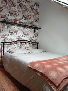um quarto com uma cama com papel de parede floral em L'essentiel em Guemps