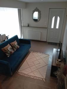 uma sala de estar com um sofá azul e um espelho em L'essentiel em Guemps