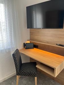 a desk with a television and a chair in a room at Hotel-Cocco-Bello in der Villa Foret in Ludwigsburg