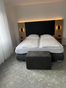 a bedroom with a large bed and a ottoman at Hotel-Cocco-Bello in der Villa Foret in Ludwigsburg