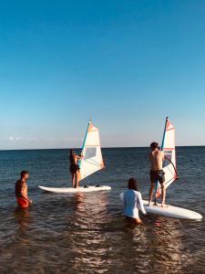 a group of people on surfboards with sailboards in the water at Denize 2 km Manzaralı ve Ferah 2+0 Daire (Konum Eşelek Köyü) in Gokceada Town