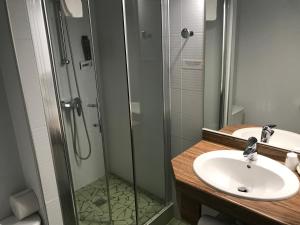 La salle de bains est pourvue d'un lavabo et d'une douche en verre. dans l'établissement Hôtel Ramuntcho, à Saint-Jean-Pied-de-Port