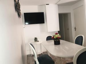 uma mesa de jantar branca com cadeiras e uma televisão na parede em La Terracotta Rer C -N104-A6 em Brétigny-sur-Orge