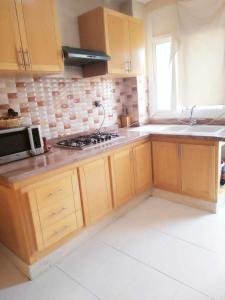 a kitchen with wooden cabinets and a stove top oven at Bel appartement plein centre avec double terrasse in Oujda