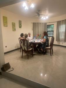 un grupo de personas sentadas alrededor de una mesa de comedor en AVIEL HOME, en Accra