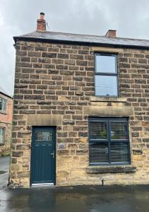 a brick building with a green door and two windows at Epworth Cottage in Crich