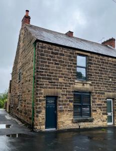 an old brick building with a blue door at Epworth Cottage in Crich