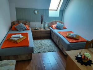 een kamer met 2 bedden met oranje lakens en een tafel bij Pansion Brod in Slavonski Brod