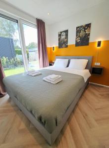 a bedroom with a large bed with two towels on it at Veluwe Home 'De Bosvogel' luxe natuurhuis in Ermelo