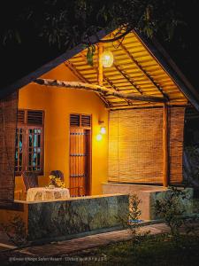 een klein huis met luifel en een tafel ervoor bij Green Village Safari Resort in Udawalawe