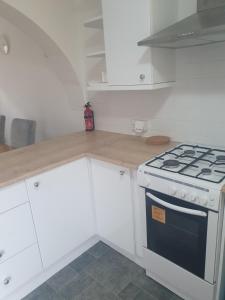 een keuken met een fornuis en witte kasten bij Quiet house 8 mins from NEC/AIRPORT in Marston Green