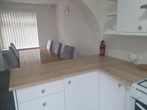 a kitchen with white cabinets and a wooden counter top at Quiet house 8 mins from NEC/AIRPORT in Marston Green