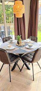 a dining room table with chairs and a chandelier at Luxe Natuurhuis Veluwe Home 'De Bosvogel' in Ermelo +19 photos