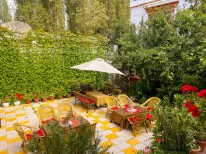 un patio con tavoli, sedie e ombrellone di Hotel shaynam a Leh