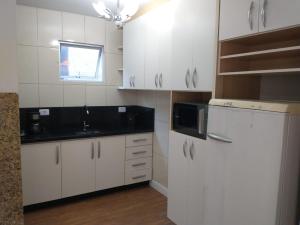 uma cozinha com armários brancos e um balcão preto em Residencial Vitor Studio 5 em São José dos Pinhais