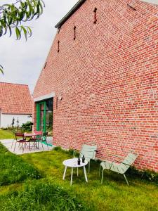 Zoersel的住宿－Origineel gerenoveerde schuur nabij Antwerpen，砖砌建筑前的两把椅子和一张桌子