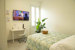 una camera con letto, scrivania e TV di Guest House Garden dei Mille a Reggio Emilia