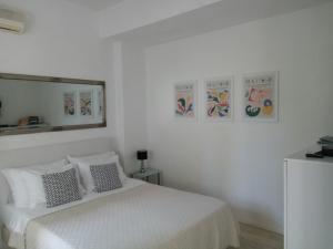 a white bedroom with a bed and a mirror at Apartments Emi in Dubrovnik