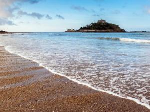 a beach with a small island in the water at bEaUtiFUL and Bright !! Town/Harbour apartment #2 in Penzance