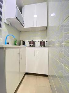 a kitchen with white cabinets and a tile wall at Dlulus Ventures Mini Flat apartment sabo in Lagos