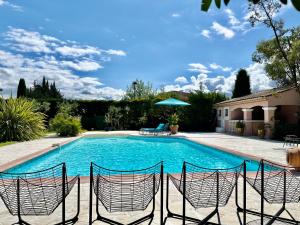 una piscina con sillas en un patio en Les Muscades, en Saint-Étienne-du-Grès