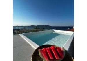 a person wearing a hat next to a swimming pool at On The Sea Suite&Spa in Methana