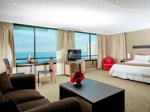 イキケにあるTerrado Club Iquiqueのベッド、デスク、椅子が備わるホテルルームです。