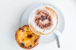 a cup of coffee and a pastry on a plate at Hotel Londres Estoril / Cascais in Estoril