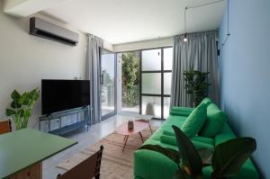 a living room with a green couch and a television at Adrop Pool Suites in Paphos
