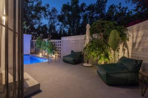 eine Terrasse mit Stühlen und einem Pool in der Nacht in der Unterkunft Adrop Pool Suites in Paphos City