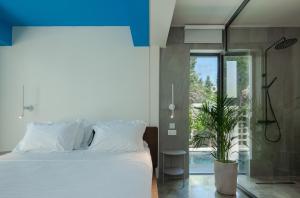 Schlafzimmer mit einem weißen Bett und einem Glasfenster in der Unterkunft Adrop Pool Suites in Paphos City