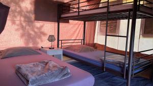 a bedroom with two bunk beds and a table with a lamp at TENTE LODGE la Plage AUTET in Autet