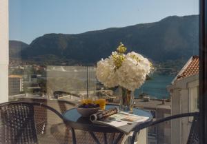 a table with a vase of flowers on a balcony at Berge Apartments in Kotor +68 photos