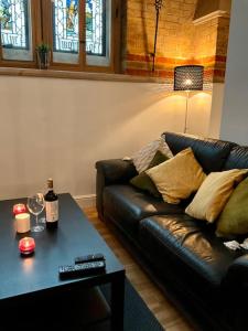 a living room with a black leather couch and a table at Magical Church Conversion in Watford in Watford
