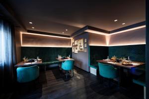 restauracja z dwoma długimi stołami i niebieskimi krzesłami w obiekcie Hotel Acadia - Adults Mountain Home w mieście Selva di Val Gardena +37 zdjęć