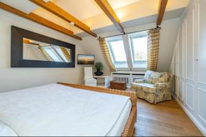a bedroom with a bed and a chair at Feriendorf Sylt Deutschland in Tinnum