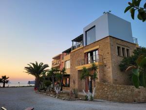 a building with palm trees in front of the ocean at Pachia Ammos Falasarna in Falasarna