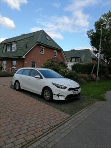 a white car parked in front of a house at Gästezimmer Mitten in Angeln in Mittelangeln