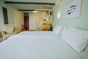 uma grande cama branca num quarto com uma cadeira em ibex unique Desert Inn em Mitzpe Ramon