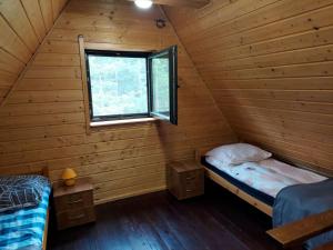 2 camas en una cabaña de madera con ventana en Chatka Góralska w Borkowie, en Borkowo