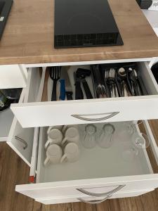 a kitchen drawer filled with dishes and utensils at Apartmán nad Bazilikou 2 in Třebíč