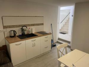 a kitchen with a sink and a table and a staircase at Apartmán nad Bazilikou 2 in Třebíč