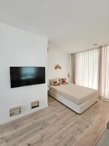 a bedroom with a bed and a flat screen tv at The Singular - Downtown Studio in Faro