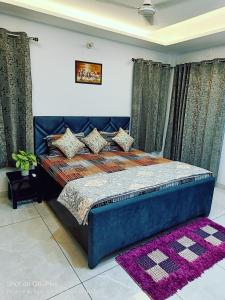 a bedroom with a blue bed with curtains and a purple rug at RASA - The Ganges Rishikesh, Ganga Bhumi Apartment in Rishīkesh