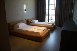 2 bedden en een bank in een kamer met een raam bij Posh Villas in Rrogozhinë