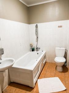 a bathroom with a tub and a toilet and a sink at Viesnīca Kandava in Kandava