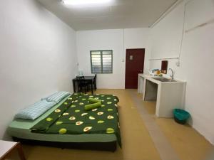- une chambre avec un lit doté d'une couverture verte dans l'établissement Padang Besar Roomstay Firdaus, à Padang Besar